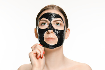 Image showing Young beautiful woman applying a mask for the face of the therapeutic black mud. Spa treatment