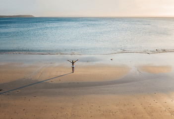 Image showing Female stands on a secluded beach at sunset