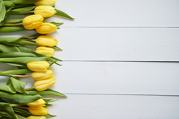 Image showing Row of fresh Yellow tulips on white wooden table