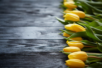 Image showing Composition of fresh yellow tulips placed in row on black rustic wooden table