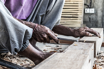 Image showing Close up of warn hands of carpenter working in traditional manual carpentry shop in a third world country.