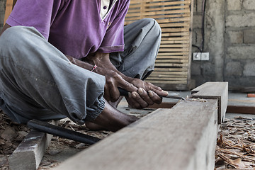 Image showing Close up of warn hands of carpenter working in traditional manual carpentry shop in a third world country.