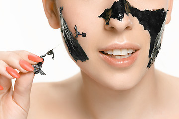 Image showing Young beautiful woman applying a mask for the face of the therapeutic black mud. Spa treatment