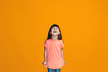 Image showing The happy teen girl standing and smiling against orange background.