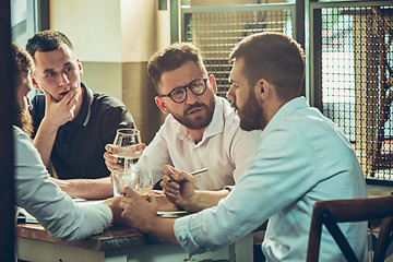 Image showing Young cheerful people smile and gesture while relaxing in pub.