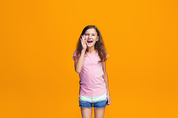 Image showing Isolated on yellow young casual teen girl shouting at studio