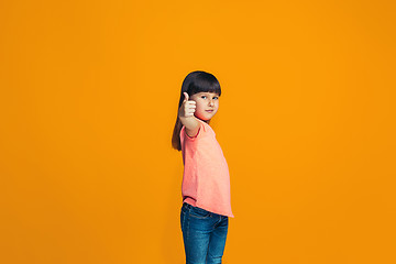 Image showing The happy teen girl standing and smiling against orange background.