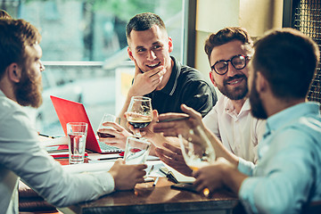 Image showing Young cheerful people smile and gesture while relaxing in pub.