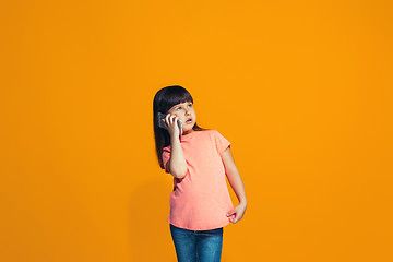 Image showing The happy teen girl standing and smiling against orange background.