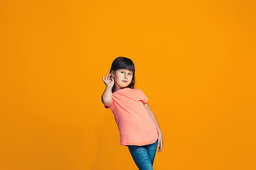 Image showing The young teen girl whispering a secret behind her hand over orange background