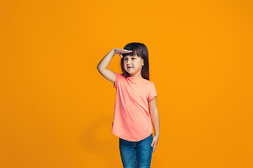 Image showing The happy teen girl standing and smiling against orange background.