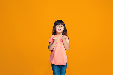 Image showing Portrait of angry teen girl on a orange studio background