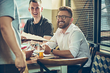 Image showing Young cheerful people smile and gesture while relaxing in pub.