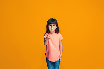 Image showing The happy teen girl standing and smiling against orange background.