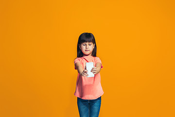 Image showing The happy teen girl standing and smiling against orange background.