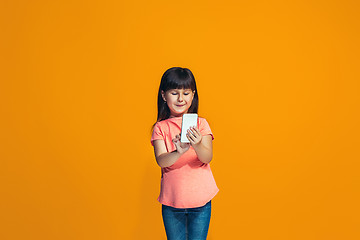 Image showing The happy teen girl standing and smiling against orange background.