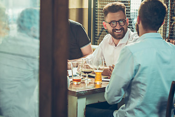 Image showing Young cheerful people smile and gesture while relaxing in pub.