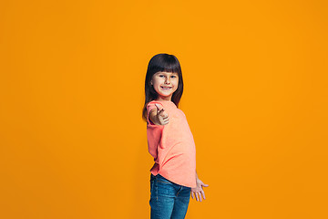 Image showing The happy teen girl pointing to you, half length closeup portrait on orange background.