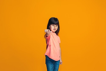 Image showing The happy teen girl pointing to you, half length closeup portrait on orange background.