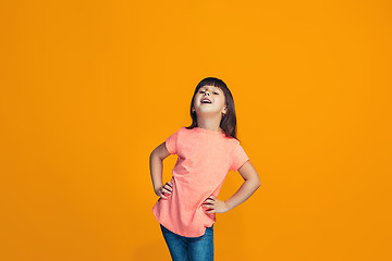 Image showing The happy teen girl standing and smiling against orange background.