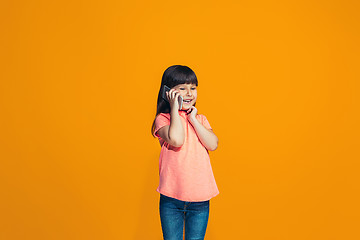 Image showing The happy teen girl standing and smiling against orange background.