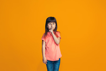 Image showing The young teen girl whispering a secret behind her hand over orange background