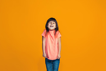 Image showing The happy teen girl standing and smiling against orange background.