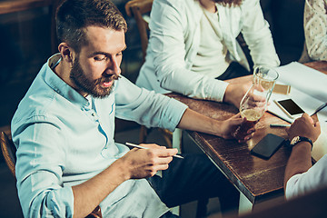 Image showing Young cheerful people smile and gesture while relaxing in pub.