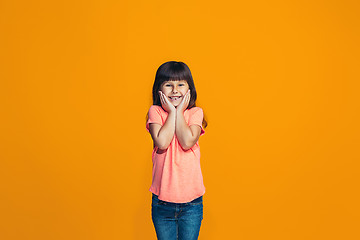 Image showing The happy teen girl standing and smiling against orange background.