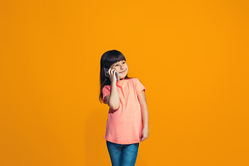 Image showing The happy teen girl standing and smiling against orange background.