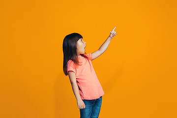 Image showing Beautiful teen girl looking suprised isolated on orange