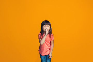 Image showing The young teen girl whispering a secret behind her hand over orange background