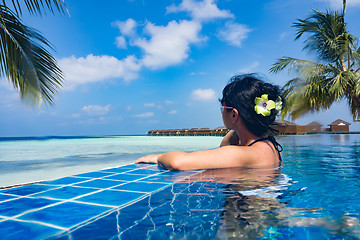 Image showing Girl looking at the ocean while sitting by the pool