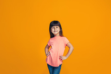 Image showing The happy teen girl standing and smiling against orange background.