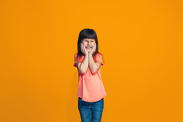 Image showing The happy teen girl standing and smiling against orange background.