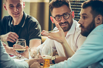 Image showing Young cheerful people smile and gesture while relaxing in pub.