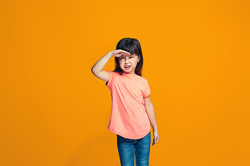 Image showing The happy teen girl standing and smiling against orange background.