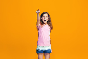 Image showing The happy teen girl pointing to you, half length closeup portrait on orange background.