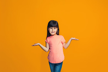 Image showing The happy teen girl standing and smiling against orange background.