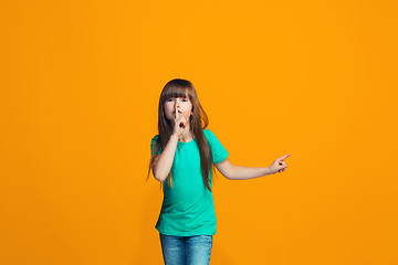 Image showing The young teen girl whispering a secret behind her hand over orange background