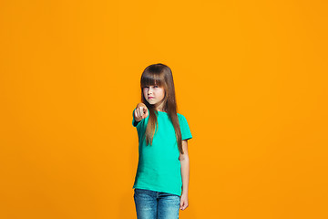 Image showing The happy teen girl pointing to you, half length closeup portrait on orange background.