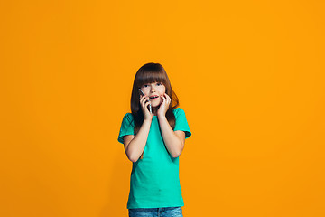 Image showing The happy teen girl standing and smiling against orange background.