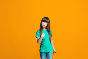 Image showing Beautiful female half-length portrait on orange studio backgroud. The young emotional teen girl