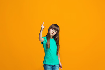 Image showing Beautiful female half-length portrait on orange studio backgroud. The young emotional teen girl