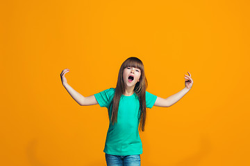 Image showing Beautiful female half-length portrait on orange studio backgroud. The young emotional teen girl