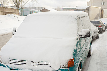 Image showing Green car is covered with snow parked near the street.