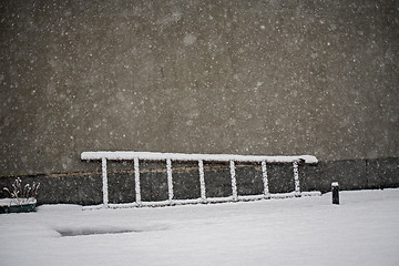 Image showing Old wooden ladder laying on the snow near the wall