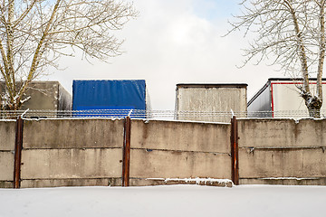 Image showing Trucks standing behind the fence wall in winter.