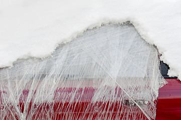 Image showing Front window of abandoned car wrapped in plastic and covered with snow.