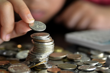 Image showing Coin piles and hand holding coin